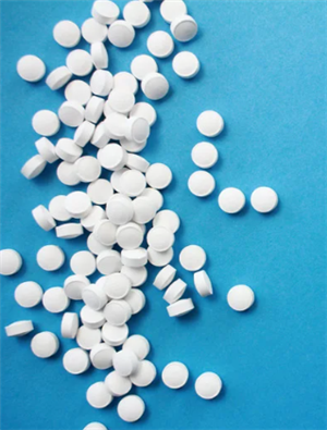 A large number of pills spilled on a table. 